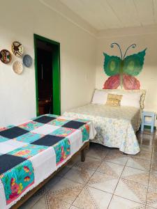 een slaapkamer met 2 bedden en een vlinder aan de muur bij Casinha hibisco in Conceição da Ibitipoca