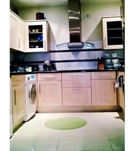une cuisine avec des armoires blanches et une machine à laver dans l'établissement The Bliss House Peaceful Retreat Close Transport Links Central London in 15mins Close to Heathrow Airport, à Harrow on the Hill