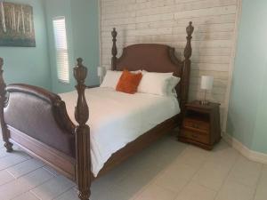 una camera da letto con un grande letto con lenzuola bianche e cuscini arancioni di Sunsets Waterfront Saltwater Heated Pool Retreat a Punta Gorda Altre 45 foto