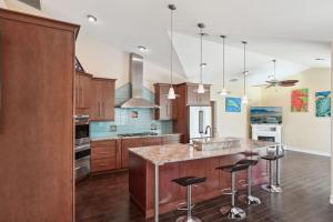 una cucina con armadi in legno e un'isola con sgabelli da bar di Sunsets Waterfront Saltwater Heated Pool Retreat a Punta Gorda