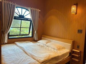 a bedroom with a large bed with a window at Giăng's House Farmstay & Glamping in Bảo Lộc