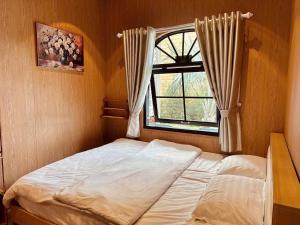 a bed in a room with a window at Giăng's House Farmstay & Glamping in Bảo Lộc