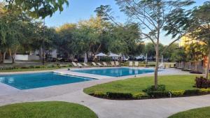 a swimming pool with lounge chairs and a tree at Boho chic, fresh, modern apartment in Ixtapa