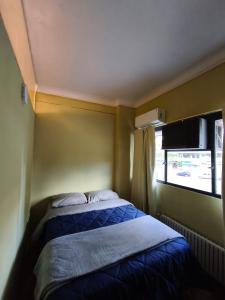 Bett in einem kleinen Zimmer mit Fenster in der Unterkunft Libertador 7 MVD in Montevideo