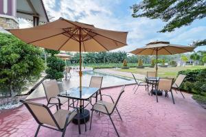 マラッカにあるLuxury Villa Hening Sari, Umbai Melaka - Smarthomeのテーブルと椅子、パラソルのあるパティオ