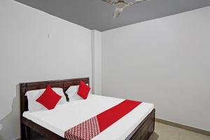 a bedroom with a bed with red and white pillows at Hotel O Sunrise Villa in New Delhi +31 photos