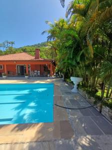 a swimming pool in front of a house with palm trees at Sítio dos Leões em Guapimirim cercado de Lazer e Natureza in Guapimirim +31 photos