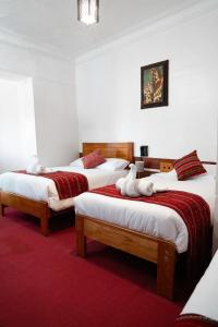 a bedroom with three beds with white towels on them at HOTEL PALACE DIAZ inn in Cusco