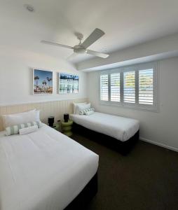 una camera da letto con due letti e un ventilatore a soffitto di The Little Tropicana a Byron Bay