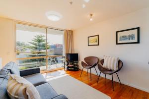 Una sala de estar con un sofá y sillas y un televisor. en Sumner Bay Motel, en Christchurch