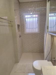 une salle de bain avec douche et toilettes et une fenêtre dans l'établissement Casa para Veraneio em Torres, à Torres