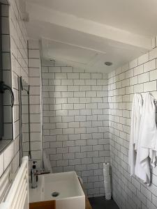 a bathroom with a sink and a white tiled wall at Suite de 35 m2 in Les Lilas +24 photos