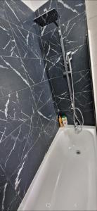 une baignoire blanche dans une salle de bains avec un comptoir noir dans l'établissement 2-room apartment with breathtaking views of Lake Geneva, à Lugrin