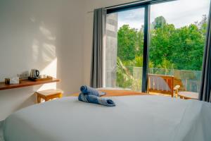 ein Schlafzimmer mit einem weißen Bett und einem großen Fenster in der Unterkunft Vasachio Guest House in Uluwatu