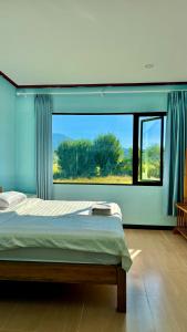 a bedroom with a bed and a large window at sokxay guesthouse in Vang Vieng