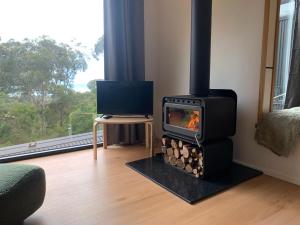 a stove in a living room with a table and a window at Perch Lorne in Lorne