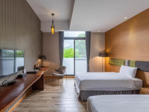 a hotel room with two beds and a desk at Hualien Toongmao Resort in Jian