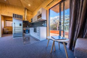 a kitchen with white appliances and a table in front of a window at Queenstown Top 10 Holiday Park in Queenstown