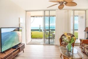 a living room with a flat screen tv and a table at Kulakane 105 · KK105 Sunsets Ocean Views Oceanfront in West Maui in Kahana