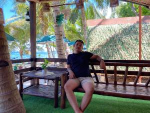 un hombre sentado en un banco en la playa en Alfonsa Tent Ground - Camp By The Sea, en Oslob 6 fotos más