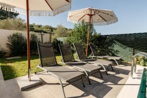 a row of chairs and an umbrella on a patio at Adelda Villa in Kypseli