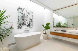 a bathroom with a tub and a sink and a mirror at Nature's Immersion Room at Anwa Bali Boutique Resort in Canggu