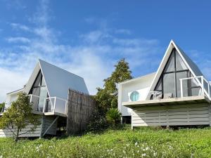 two houses on top of a grassy hill at Pak Himdoi Farm Homestay สวนผักฮิมดอยโฮมสเตย์ ฝาง in Ban Wiang Kok