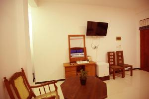 a living room with a table and a tv on a wall at White Lion Paradise Dikwella in Batigama