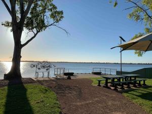 tavolo da picnic e panche accanto all'acqua di Cosy on Colless a Mulwala