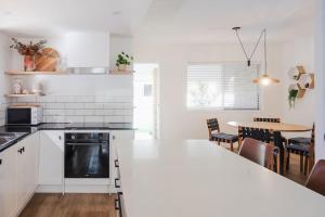 Una cocina con gabinetes blancos y una mesa con sillas. en Whitsunday Wanderluxe, en Cannonvale 22 fotos más