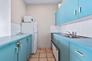 a kitchen with blue cabinets and a white refrigerator at Ocean View Apartment 14 in Airlie Beach
