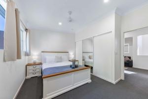 una camera da letto bianca con un letto e uno specchio di Tropical Resort Apartment a Cannonvale