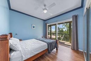 a bedroom with blue walls and a bed and a window at Treetop Paradise Retreat with Pool in Cannonvale