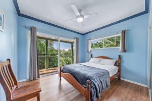 a blue bedroom with a bed and a window at Treetop Paradise Retreat with Pool in Cannonvale
