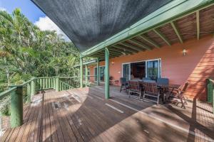 a deck with a table and chairs on a house at Treetop Paradise Retreat with Pool in Cannonvale