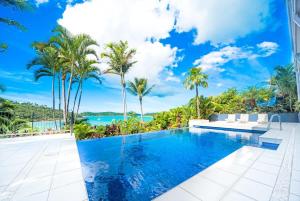 a swimming pool in a villa with palm trees at Baybliss Escape #2 - Adults Only in Shute Harbour +3 photos