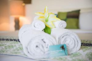 a pile of towels and a flower on a bed at Baybliss Escape #3 - Adults Only in Shute Harbour