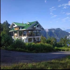 a large house with a green roof on a hill at Wanderlust Homestay By StayApart in Kalimpong