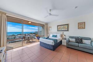 a bedroom with a bed and a couch and a balcony at OCEAN VIEWS 10A in Airlie Beach