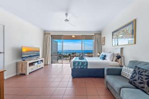Un dormitorio con una cama y una sala de estar con un sofá. en OCEAN VIEWS 10A, en Airlie Beach