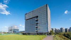 Un edificio alto de cristal en una ciudad con un parque. en Holiday Inn Express Kunming Changshui Airport by IHG, en Kunming