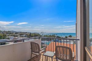 ein Balkon mit zwei Stühlen und Blick auf das Meer in der Unterkunft OCEAN VIEWS 10 in Airlie Beach