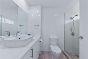 ein weißes Badezimmer mit Waschbecken und Toilette in der Unterkunft OCEAN VIEWS 10 in Airlie Beach + 26 Fotos