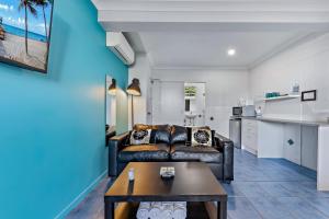 a living room with a leather couch and a table at Airlie Sun & Sand Accommodation #2 KIDS STAY FREE in Airlie Beach +40 photos