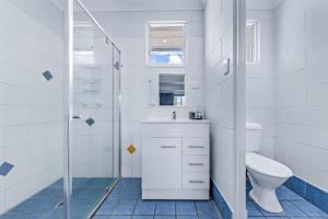 a white bathroom with a toilet and a shower at Airlie Sun & Sand Accommodation #3 KIDS STAY FREE in Airlie Beach +36 photos