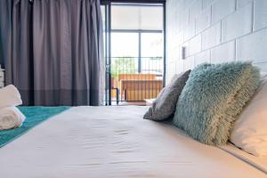 a bed with pillows on it in a room at Airlie Sun & Sand Accommodation Studio #1 KIDS STAY FREE in Airlie Beach +34 photos