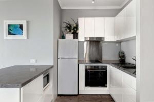 eine Küche mit weißen Schränken und einem weißen Kühlschrank in der Unterkunft OCEAN VIEWS 16 pool & Spa Wi-FI in Airlie Beach