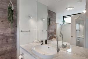 ein weißes Badezimmer mit Waschbecken und Spiegel in der Unterkunft Ocean View 16A Studio Pool & Spa Wi-Fi in Airlie Beach