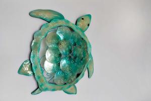 eine grüne Meeresschildkröten-Wandskulptur an einer weißen Wand in der Unterkunft Ocean View 16A Studio Pool & Spa Wi-Fi in Airlie Beach