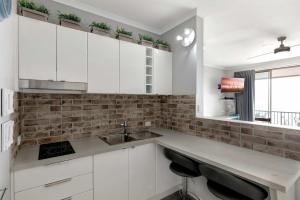 eine Küche mit weißen Schränken und einer Spüle in der Unterkunft Ocean View 16A Studio Pool & Spa Wi-Fi in Airlie Beach + 25 Fotos
